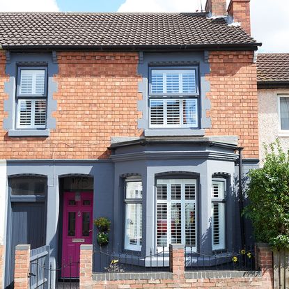 home exterior with red brick wall and bay window with pink door