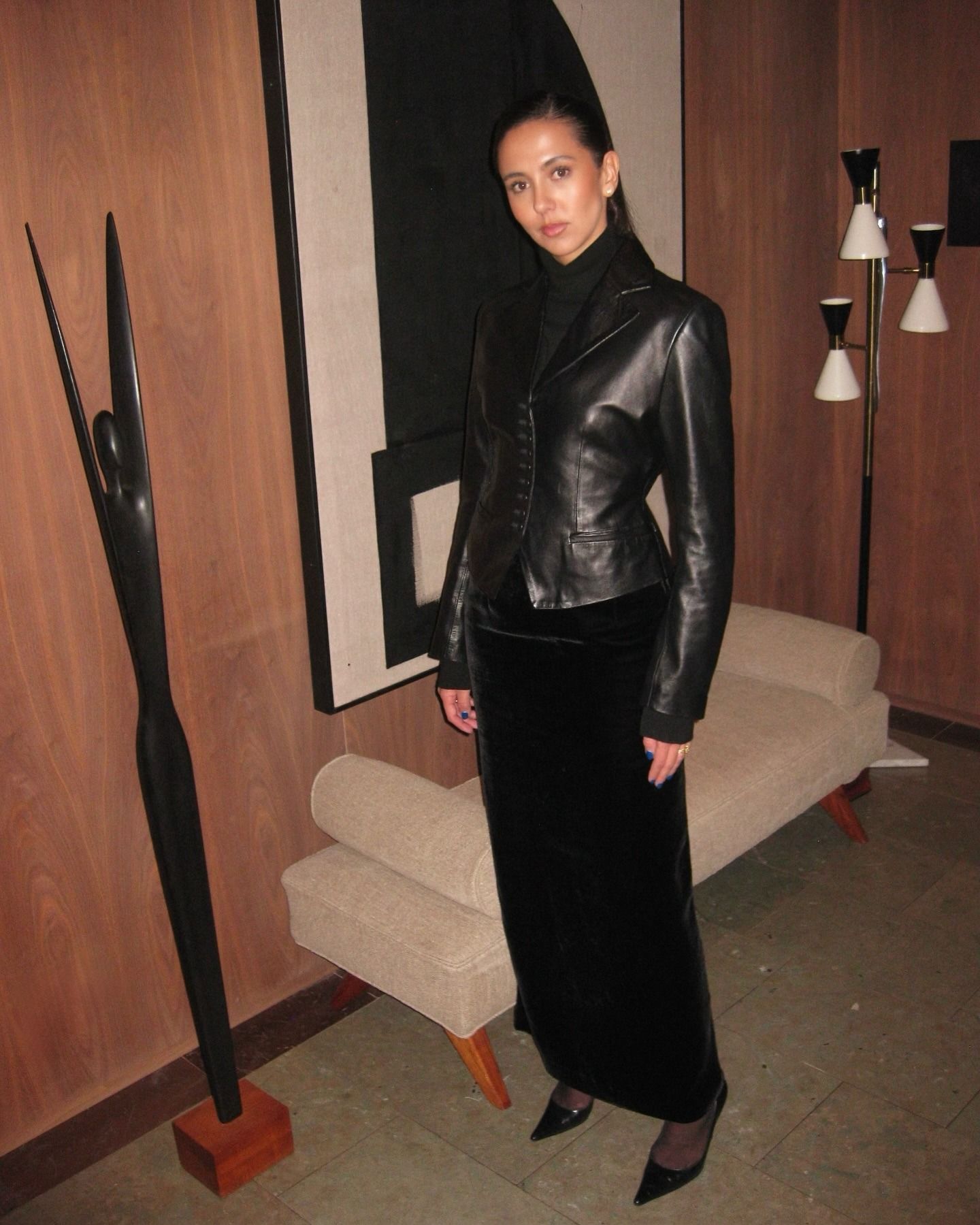 Hanna wears a leather blazer, turtleneck, velvet skirt and pumps.