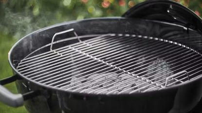 Portable gas bbq on a patio with light grey outdoor tiles and a wicker outdoor seat