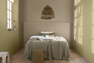 A yellowy beige bedroom with a taupe accent wall and wooden floorboards