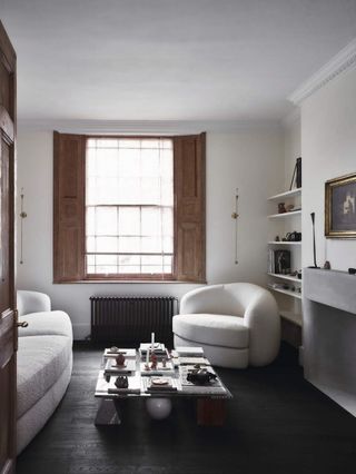 A white living room with neutral sofas and black flooring