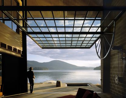 Tom Kundig's iconic Chicken Point Cabin inside with man looking out towards the water