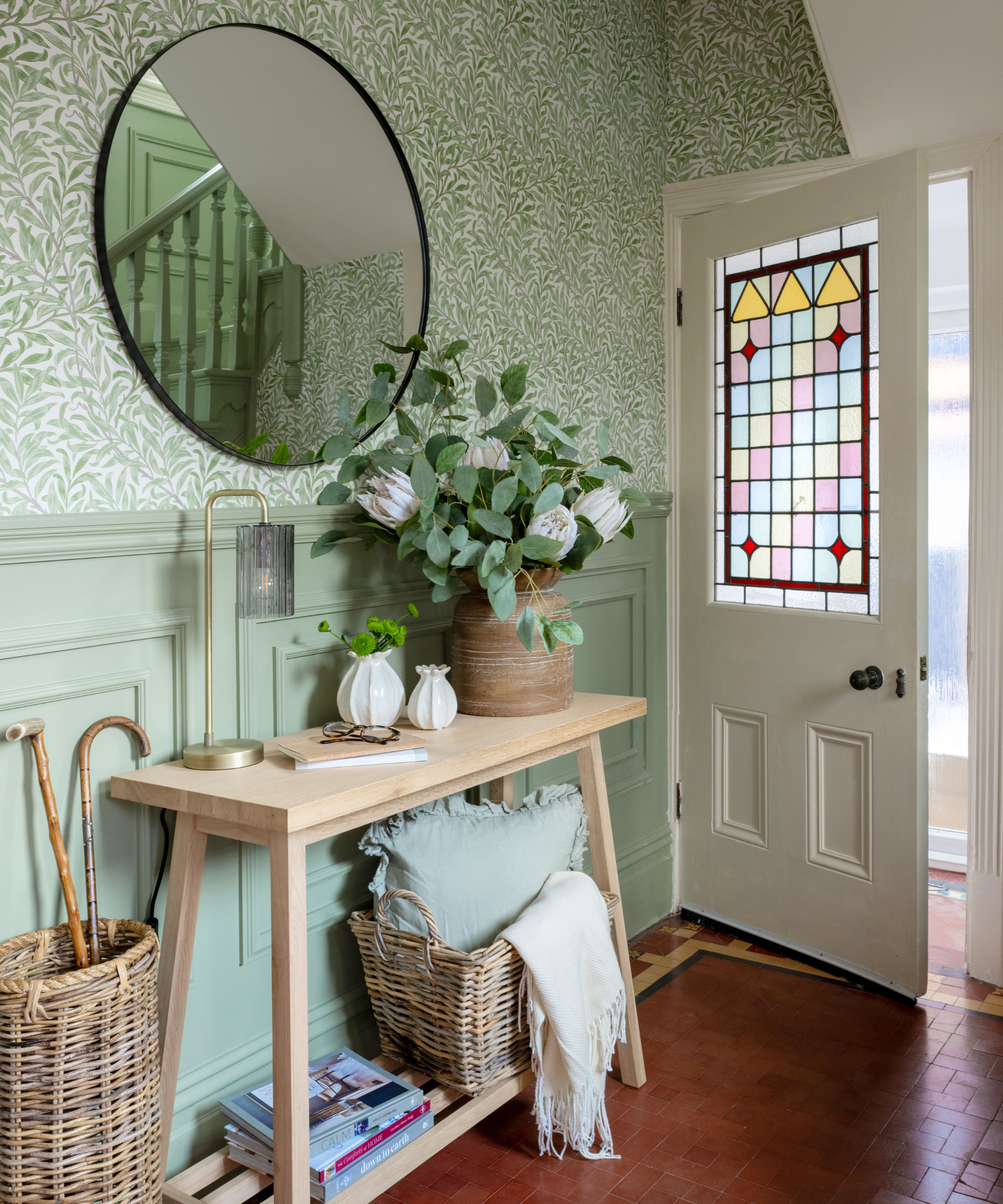 Light green hallway with half panelling and a mirror opposite stairs