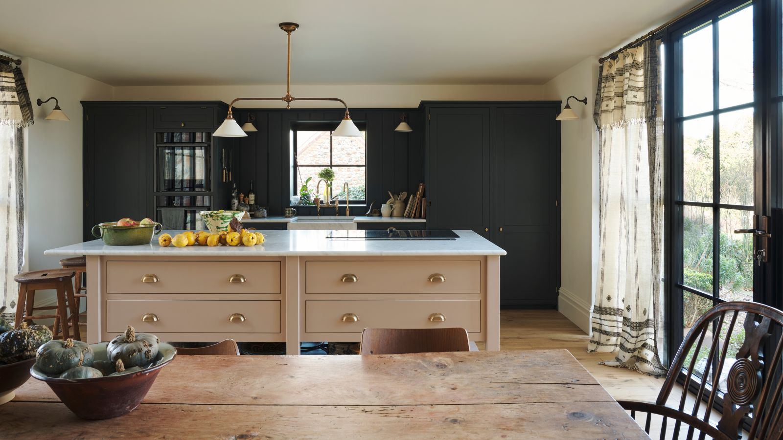 Bright cottage kitchen with dark green cabinets and warm pink island