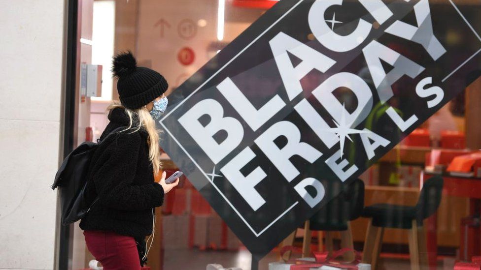 Una mujer frente a un escaparate que muestra un cartel de ofertas del Black Friday