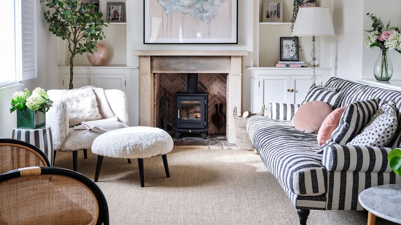 Country-style living room with log burner, cream carpets, a black and white striped sofa on the right wall and an accent chair on the left