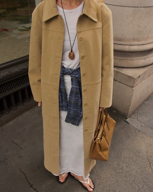 @chloekathbutler wears a tartan shirt tied around over waist over a cream maxi dress and finished with a butter yellow suede coat