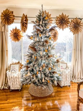 A farmhouse-style Christmas tree with frosted effect, woven stand and brown paper decorations