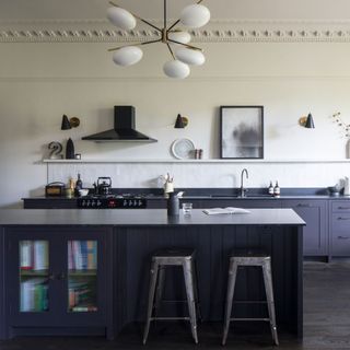 a grey neutral galley kitchen with cooker hood, Tolix metal bar stools and a decorative pendant