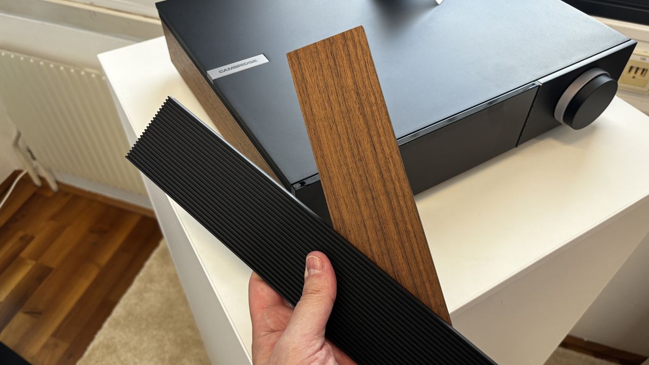 A hand holding two different side panels for the Cambridge Audio Evo 300