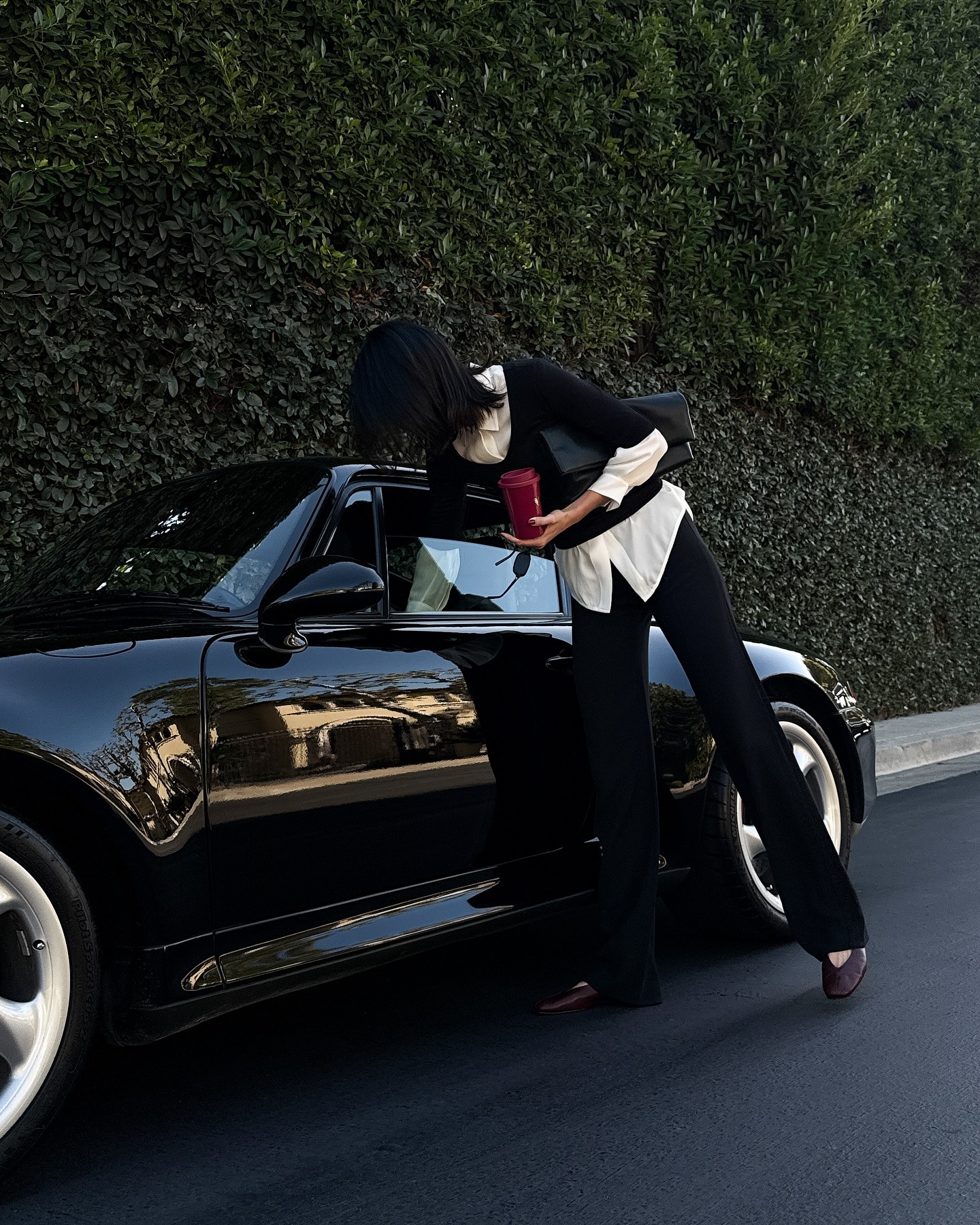 Kendall Jenner wears black trousers with a white shirt and a black v-neck knit.