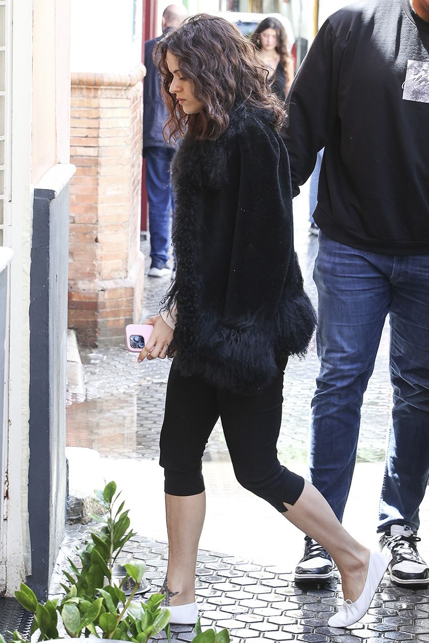 Rosalia wearing a fur-trimmed jacket with black capri pants and white ballet flats