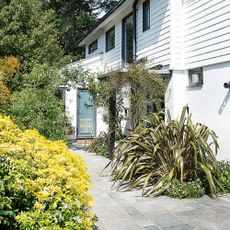 Block paving path leading to front door, surrounded by flower beds