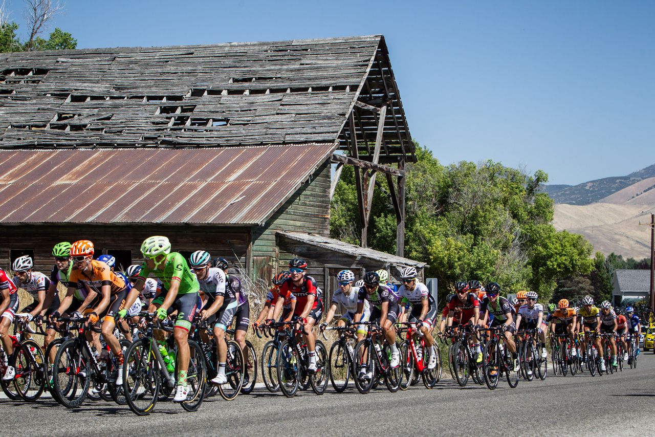 The peloton passes an old barn along the course