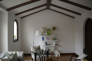 A white living room with vaulted ceiling with wooden beams