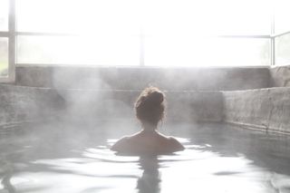 Woman swimming in thermal pool with steam rising