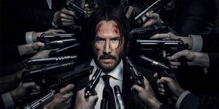 John Wick stands with a whole bunch of guns surrounding his head in a promotional image for the John