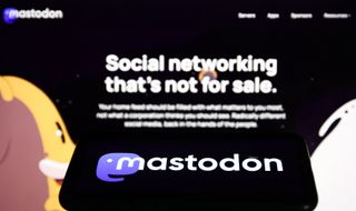 The Mastodon logo in a phone in front of its website