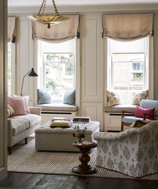 traditional living room with dark wooden floor and neutral sofas with a patterned armchair and a large ottoman