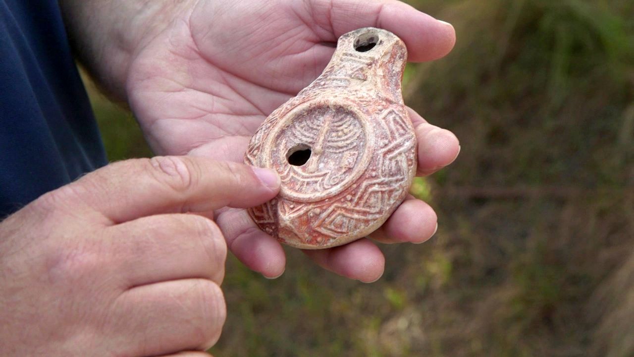 A man holds a carved clay lamp in his hands