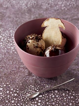 Purple and white speckled background, roasted mushrooms with ice cream dish in a pink bowl, silver spoon