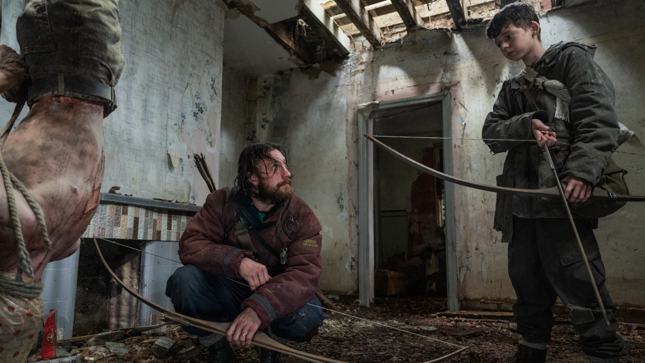 Aaron Taylor-Johnson looks up at Alfie Williams as they stand by a hanging Infected in 28 Years Later.