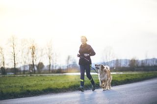 A woman running on a road with her dog