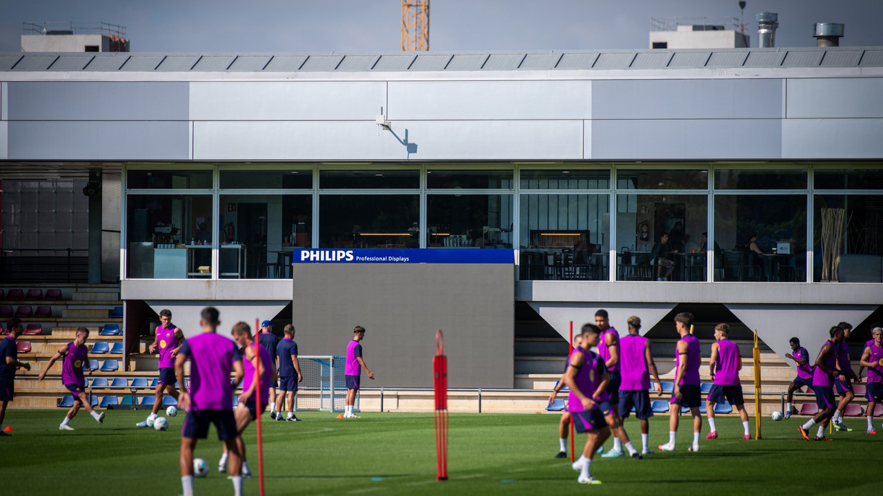 Soccer players in purple jerseys warm up on the pitch. 