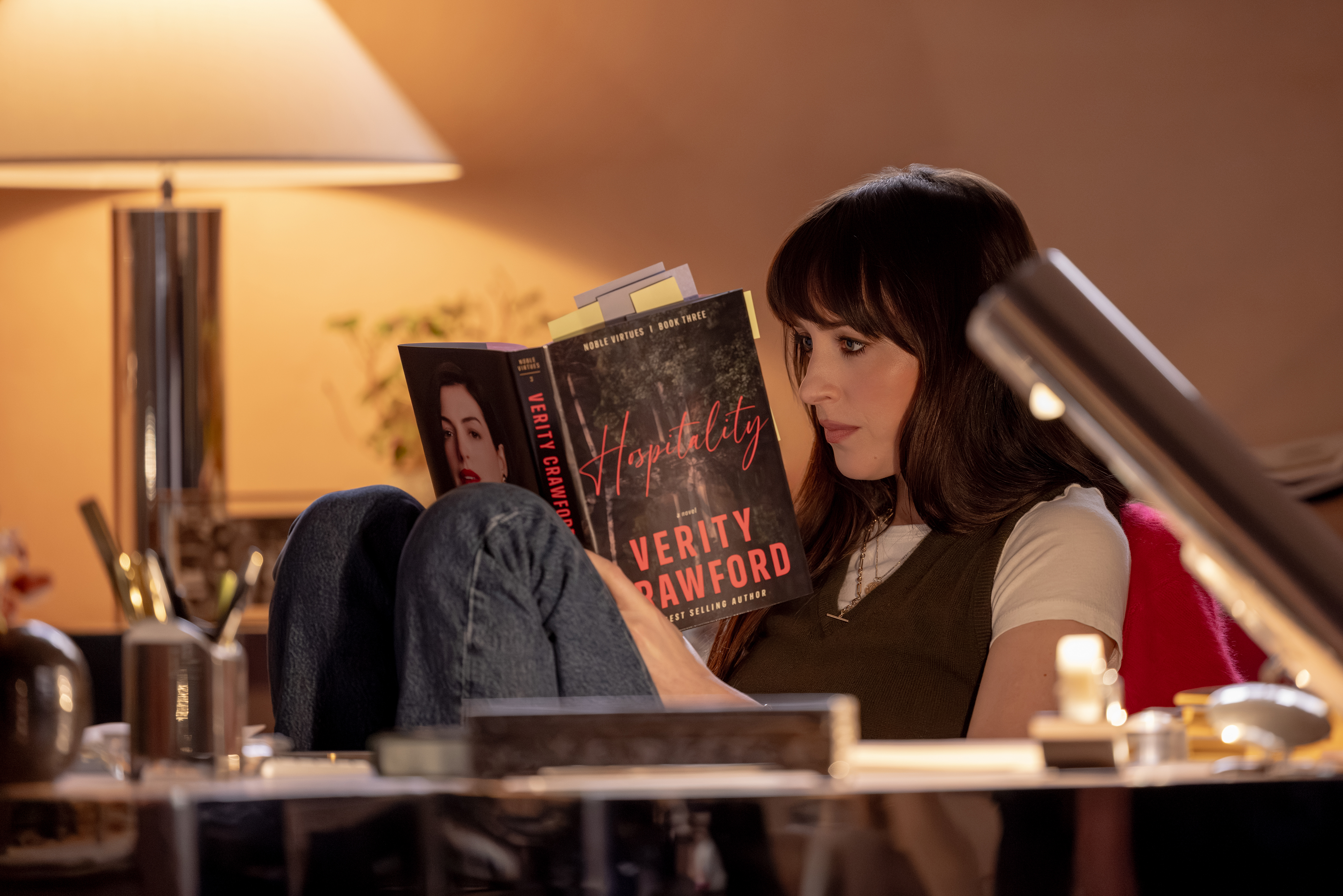 Dakota Johnson stars as Lowen Ashleigh reading a copy of the book verity at a desk in the movie adaptation of verity