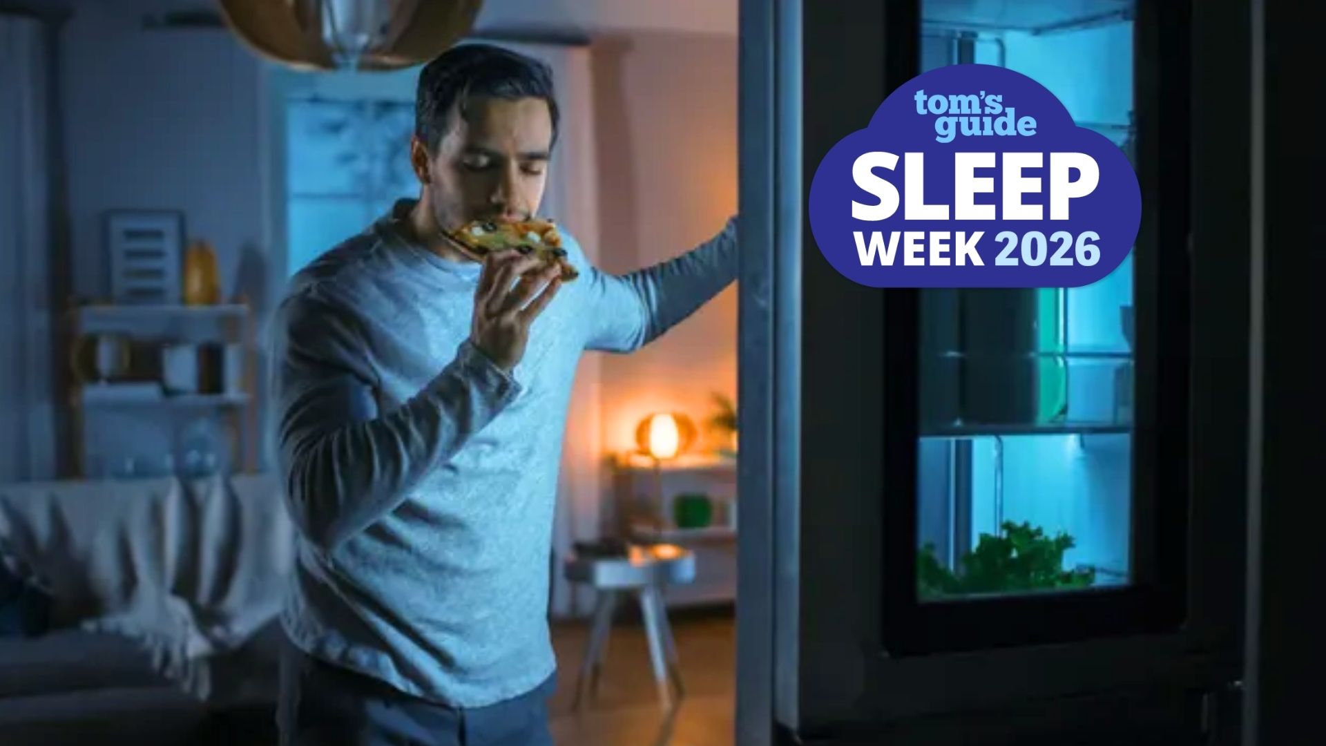 The image shows a dark-haired man standing at his fridge, holding a slice of pizza to his mouth with the fridge door still open. Overlaid on top of the image in the top left hand corner is a blue cloud-shaped badge that read Tom's Guide Sleep Week 2026. 