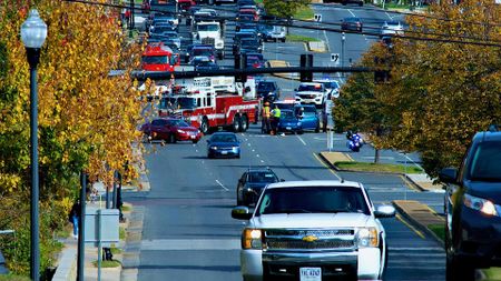 photo of a fire truck, ambulance and police vehicles blocking off traffic at an intersection where a crash appears to have taken place