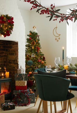 rustic farmhouse Christmas dining room, with tree, log burner, wrapped presents, wreath
