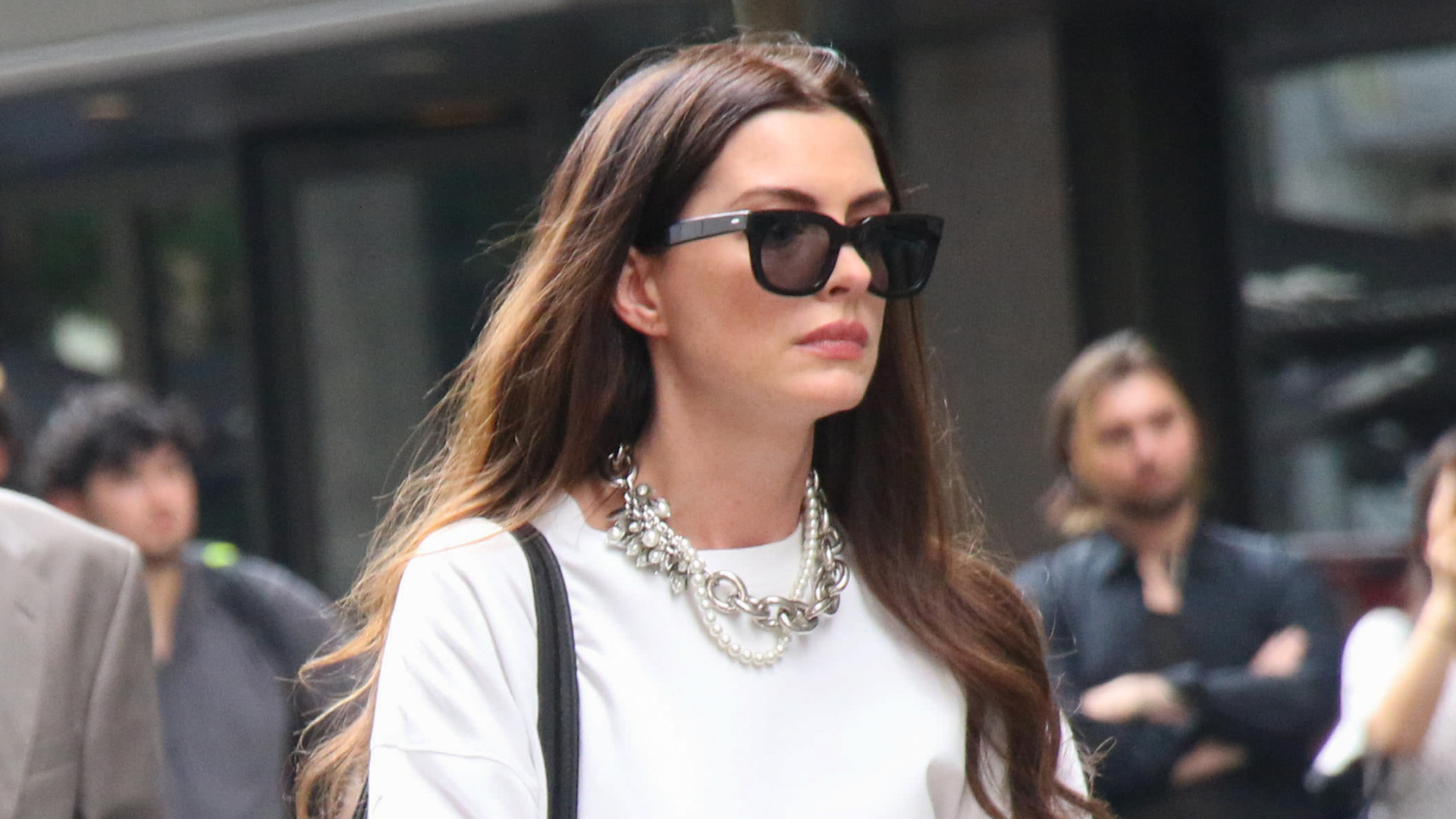 Anne Hathaway films The Devil Wears Prada 2 wearing white pants and a white top and carrying a vintage Coach briefcase