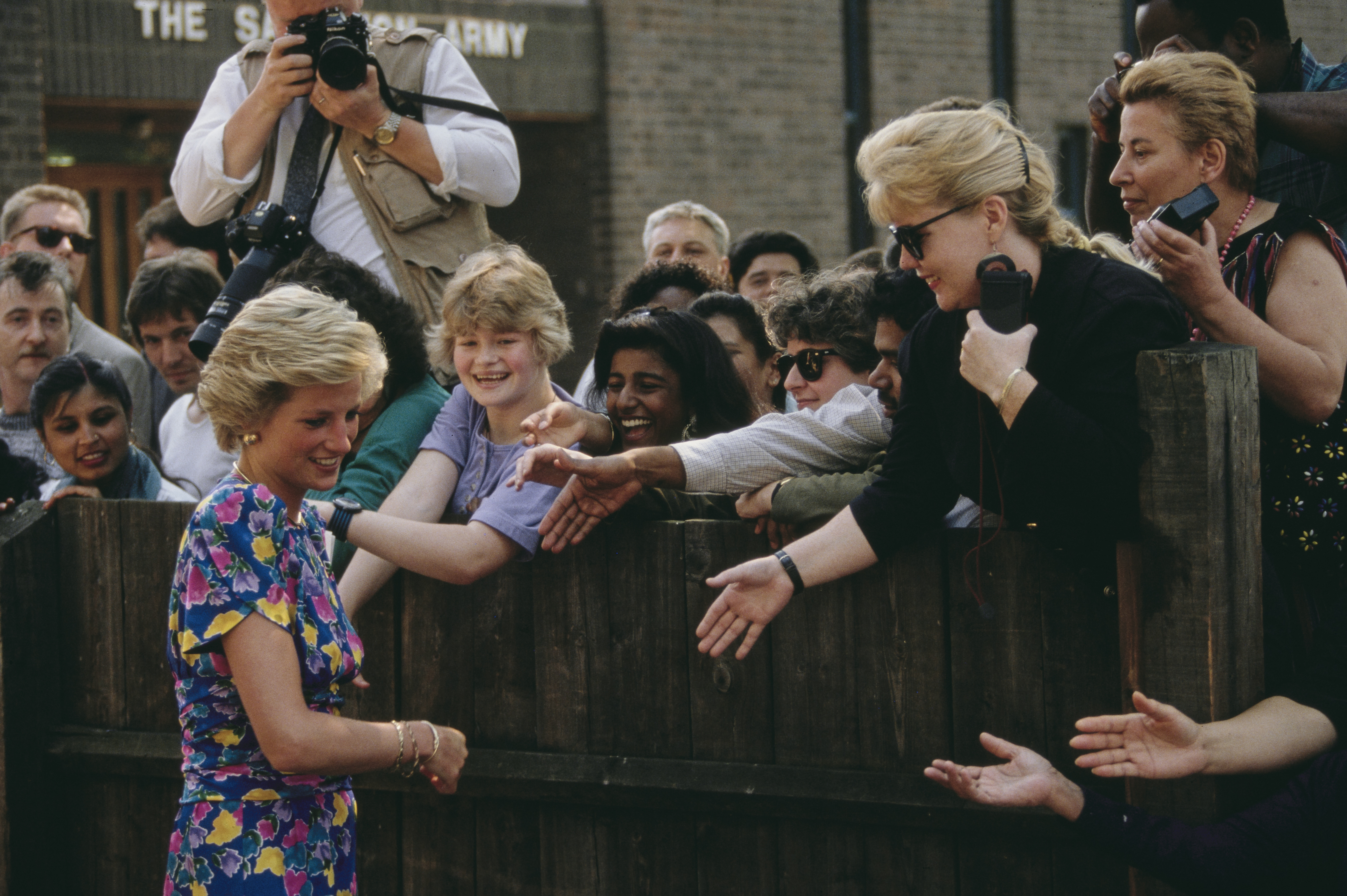 Fans reach over a fence to try and shake Princess Diana's hand in 1990.