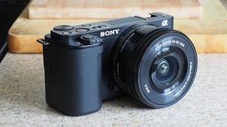 The Sony ZV-E10 camera on a marble surface in front of a wooden board