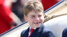 Prince Louis smiles as he travels by carriage during Trooping the Colour 2025