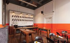 Bar with lower-half of walls in vibrant orange. Dark wood tables and chairs