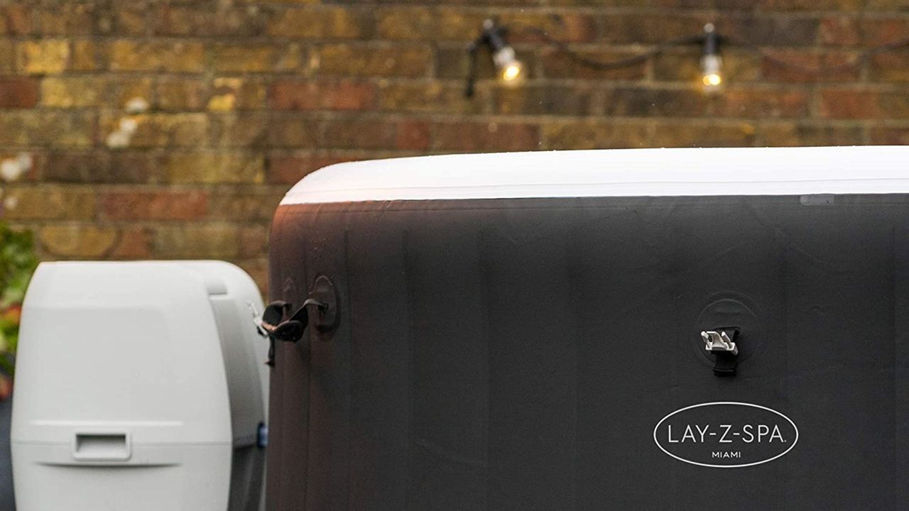 Lay-Z-Spa Miami black hot tub close up in front of brick wall with festoon lighting