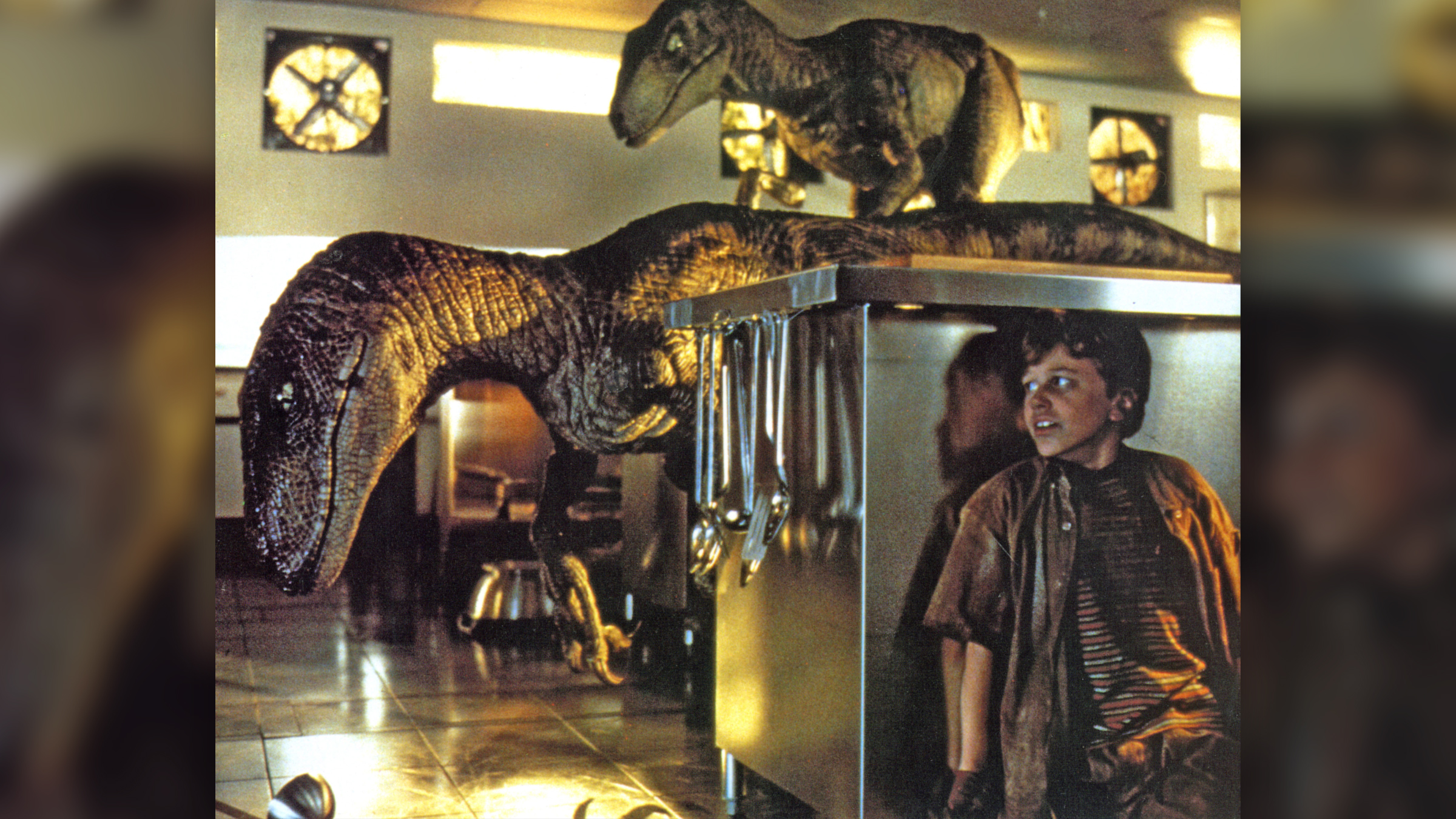 In a scene from the 1993 movie Jurassic Park, a boy hides in the kitchen from two velociraptor dinosaurs.