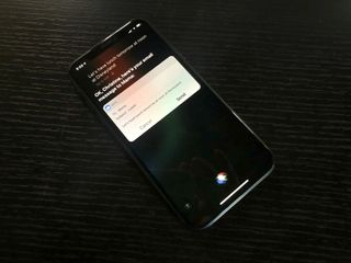 iPhone XS on black wood table with Siri sending email