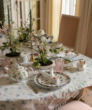 spring easter tablescape with a floral tablecloth and floral vintage tableware with potted plants