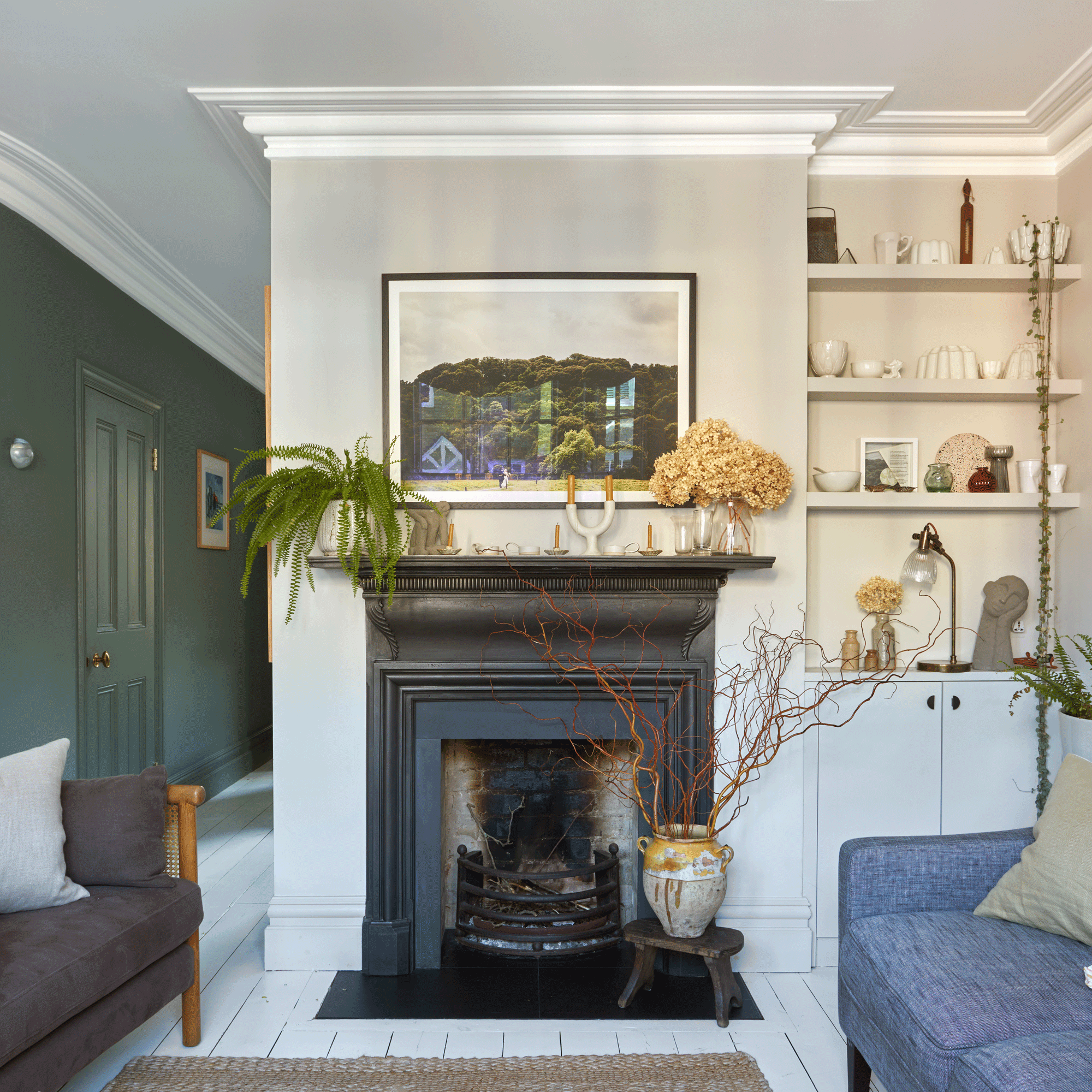 a living area with a fireplace and alcove shelving beside a dark grees hallway wall