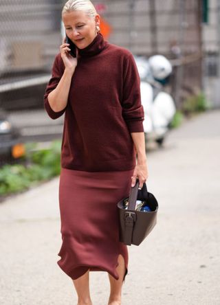 A woman in New York wearing a burgundy jumper and matching silk maxi skirt.