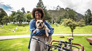 Woman holding a dog with her bike next to her