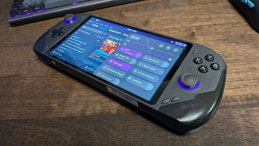 A handheld gaming PC on a desk running Bazzite, a Linux OS, on-screen.