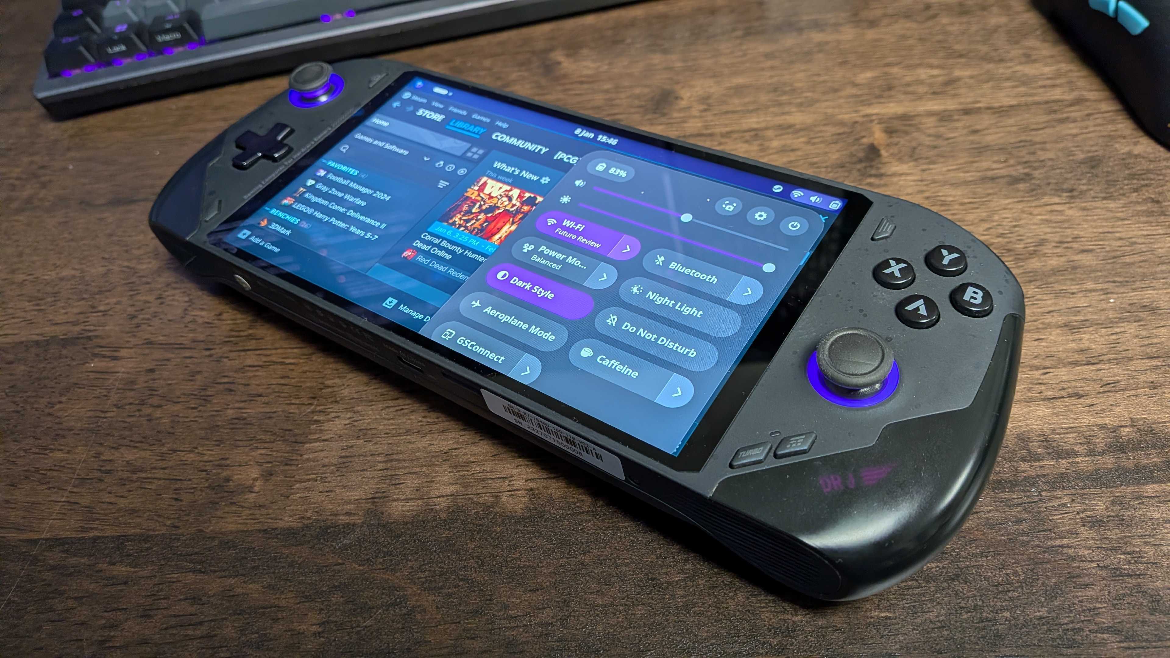 A handheld gaming PC on a desk running Bazzite, a Linux OS, on-screen.