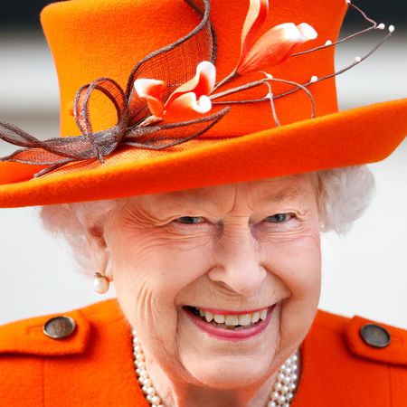 Queen Elizabeth smiling in an orange coat and hat