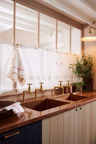 copper sink with bib taps and cafe curtains above