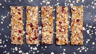 A selection of cereal bars made of oats and dried fruit on black slate table top, an example of what to eat before a workout