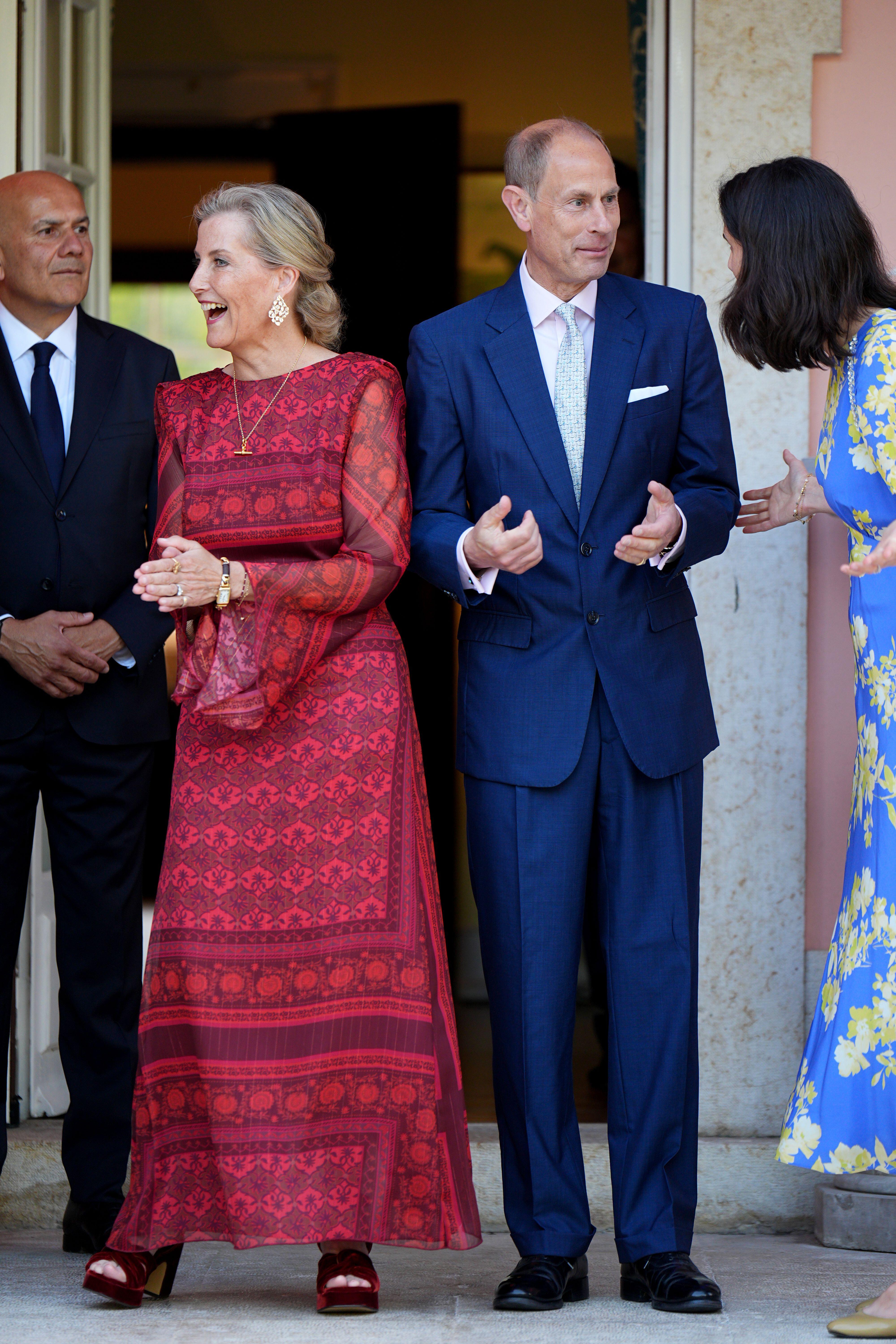 Duchess Sophie in a red dress laughing and standing next to Prince Edward